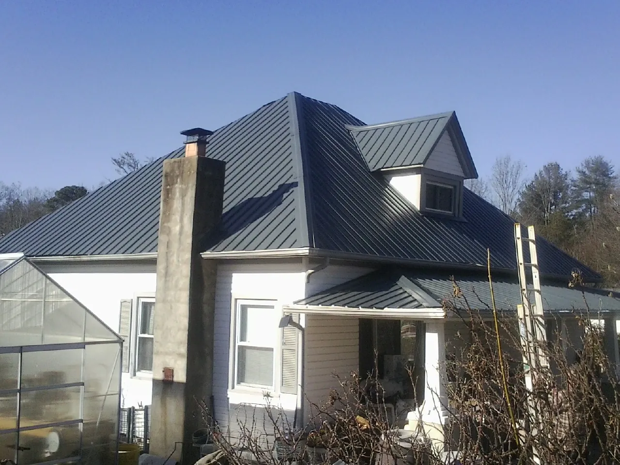 Dark blue standing seam metal roof on a white farmhouse with dormer — Slate & Tile Roof Repair by Roofing Brothers in Peninsula