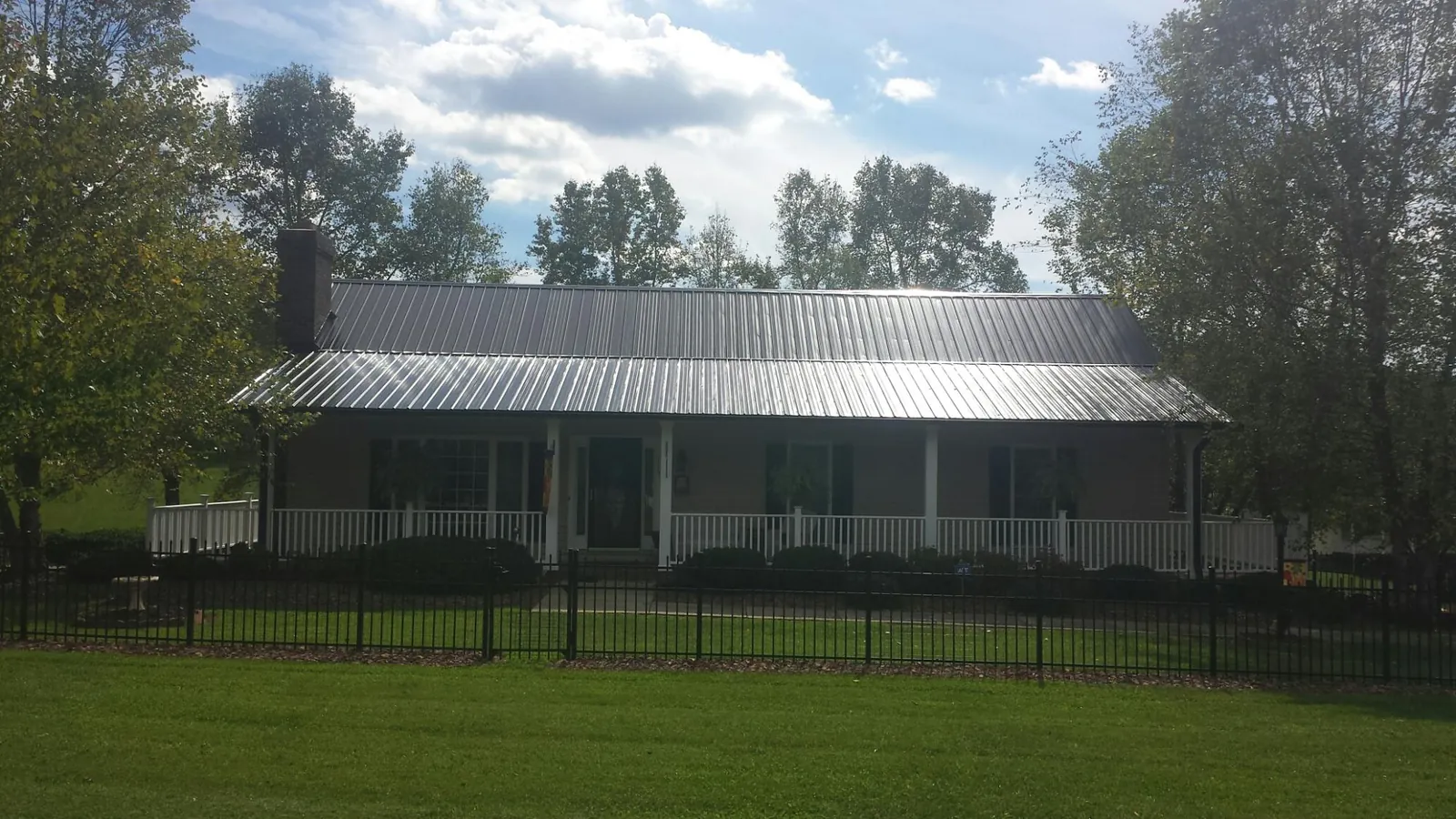 Gray metal roof on a brick ranch with a full width front porch — Gutter Guard Installation work by our crew in Peninsula
