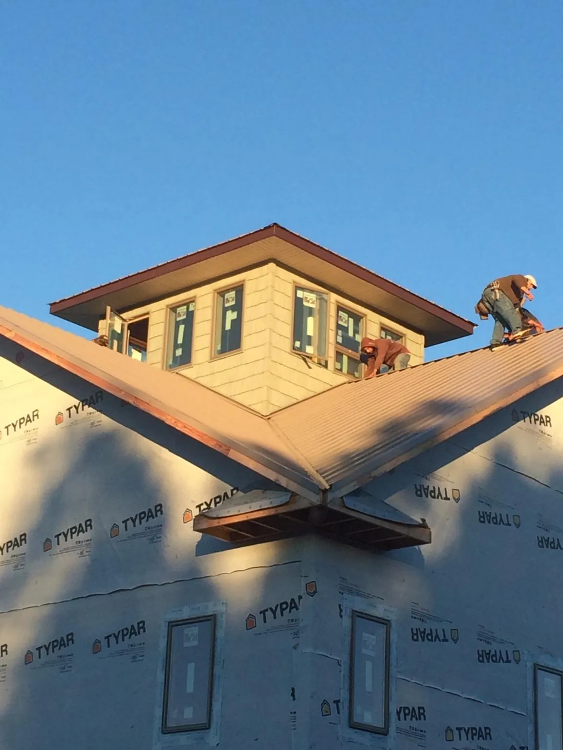 Roofers working around a rooftop cupola on a new metal roof at sunset — Roof Waterproofing in Peninsula by Roofing Brothers
